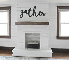 a white fireplace with the word gather painted on it's mantle and windows in the background