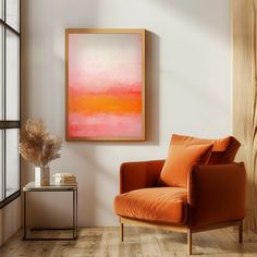 an orange chair sitting in front of a window next to a painting on the wall