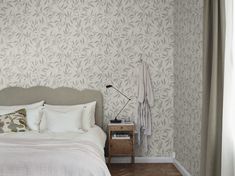 a white bed sitting next to a window in a bedroom under a light colored curtain