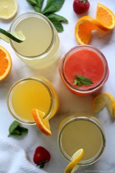 three glasses filled with different types of drinks and garnished with oranges, strawberries, mint leaves and lemon slices