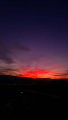 the sun is setting over some hills and trees