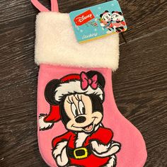 a minnie mouse christmas stocking hanging on a wooden floor with a tag attached to it