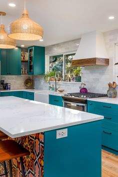 a large kitchen with blue cabinets and white counter tops, an island in the middle