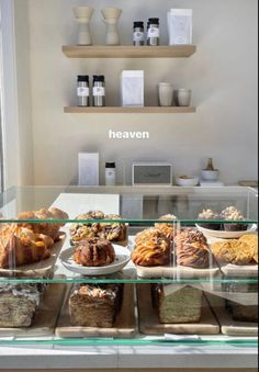 a display case filled with lots of different types of breads and pastries on top of glass shelves