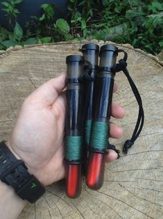 three green and red pens sitting on top of a tree stump