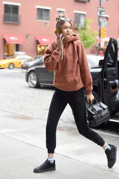 a woman is walking down the street talking on her cell phone and holding a purse