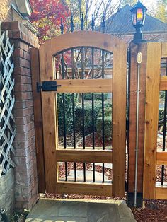 a wooden gate with wrought iron bars on the top and bottom, in front of a brick house