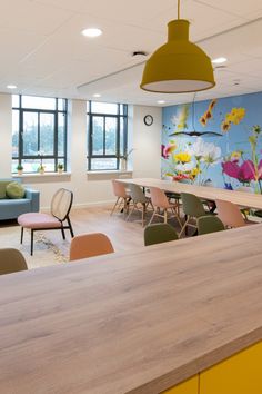 an office with chairs, tables and couches in front of a colorful wall mural