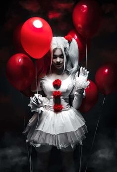 a woman dressed in white holding red balloons