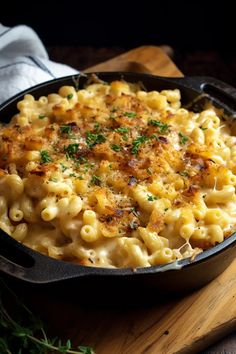 macaroni and cheese in a cast iron skillet on a wooden cutting board