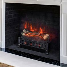 a fire is burning in a fireplace with white walls and black tile on the floor