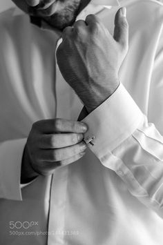 black and white photograph of a man adjusting his collar on his dress shirt, taken from the waist up