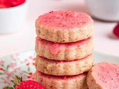 strawberry shortbread cookies stacked on top of each other with strawberries in the background