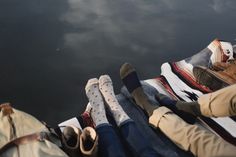 two people are sitting on the dock with their feet propped up against each other's legs