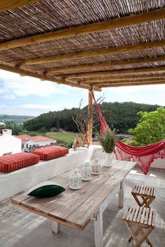 a wooden table sitting on top of a patio next to a hammock