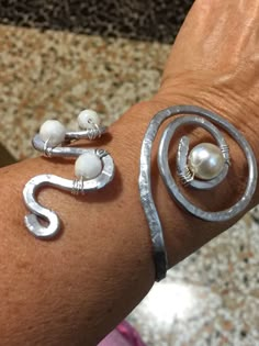 a close up of a person's arm with two rings and pearls on it