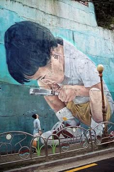 a man walking past a large painting on the side of a building next to a street