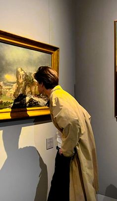 a man standing next to a painting in a museum looking at it's reflection