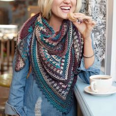 a woman with blond hair wearing a scarf and holding a donut