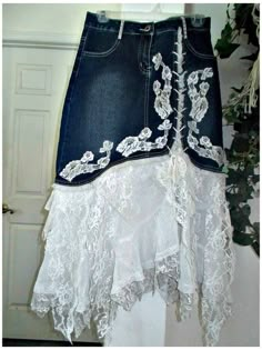 a skirt with white lace on it hanging from a wall next to a potted plant