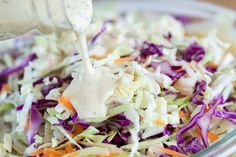 a salad with dressing being poured onto it and garnished with coleslaw