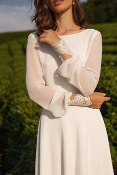 a woman in a white dress is posing for the camera with her hand on her shoulder