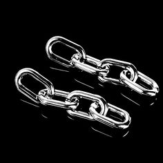 two silver chain links on a black surface with one metal link attached to the other