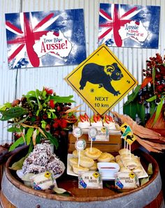 a table topped with lots of pastries and desserts next to flags on the wall