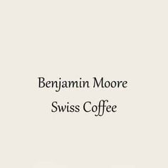 a coffee cup sitting on top of a wooden table next to a white wall with the words benjamin moore swiss coffee