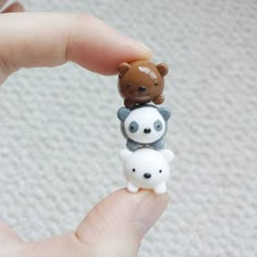 a hand holding a tiny toy with two small bears on it's back and one smaller bear sitting on top of the other