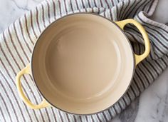 a yellow pan sitting on top of a white and gray striped cloth next to a knife