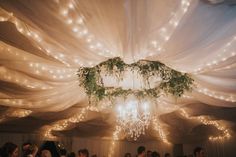 a room filled with lots of people under a canopy covered in white draping