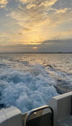 the sun is setting over the water as seen from a boat in the ocean with waves