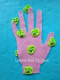 a hand made out of felt with green buttons on the palm and two fingers that have smiley faces