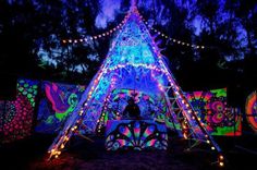 a lit up tent in the dark with lights all around it and decorations on top