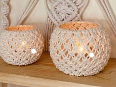 two white crocheted baskets sitting on top of a wooden shelf