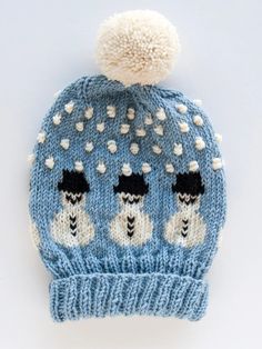 a blue knitted hat with white pom - poms on the front and back