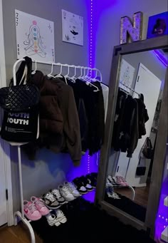 a closet with clothes and shoes hanging on the rack in front of a large mirror