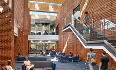 people are sitting on couches and chairs in the lobby area of a large building