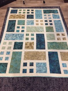 a blue and green patchwork quilt on a wooden floor