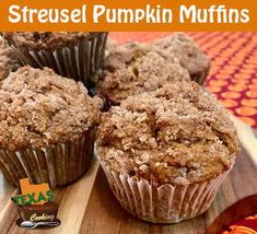 three muffins on a wooden board with the title streusel pumpkin muffins