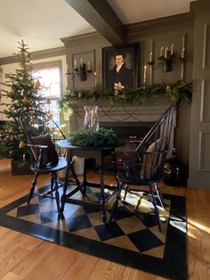 two chairs sitting at a table in front of a fire place with a christmas tree