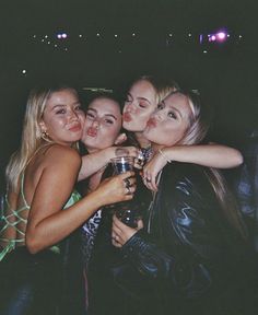 four women are posing for the camera with drinks