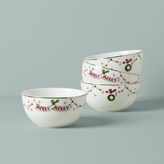 three white bowls with christmas designs on them sitting side by side in front of a gray background