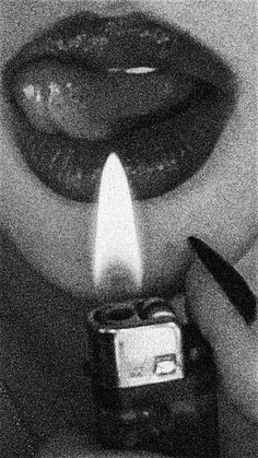 a black and white photo of a person holding a lighter in front of their face