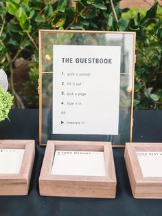 the guest book is set up on a table next to two small wooden frames with flowers in them