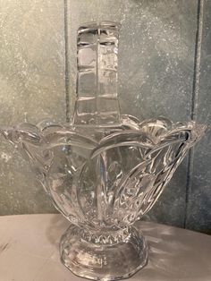 a clear glass vase sitting on top of a white table next to a gray wall