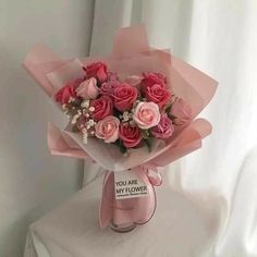 a bouquet of pink roses sitting on top of a white table