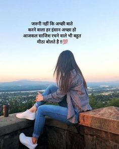 a woman sitting on top of a stone wall