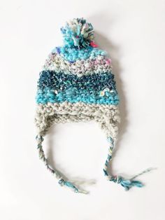 a crocheted hat with pom - poms on it sitting on top of a white surface